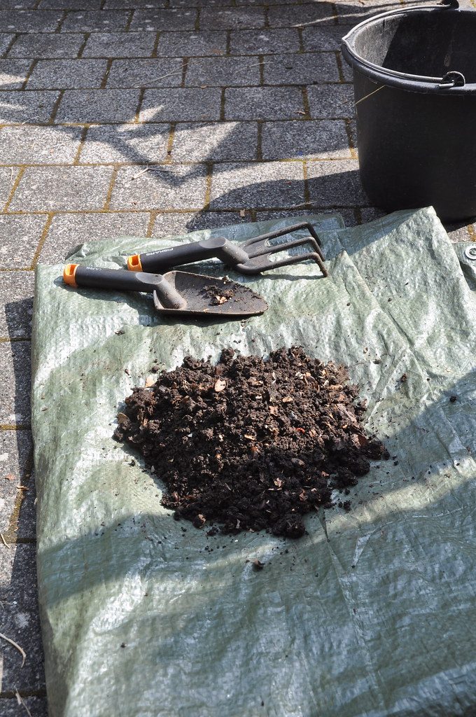 Comparison of organic fertilizer materials including compost, bone meal, and fish emulsion on a potting bench